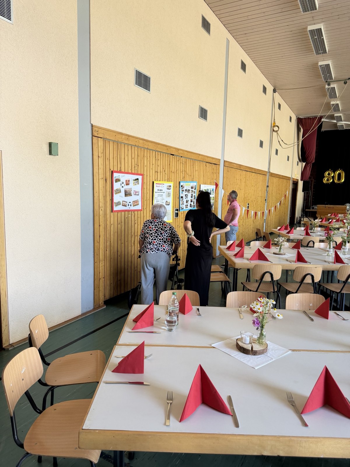Besucher betrachten Ausstellungstafeln zur Vereinsgeschichte an der Hallenwand