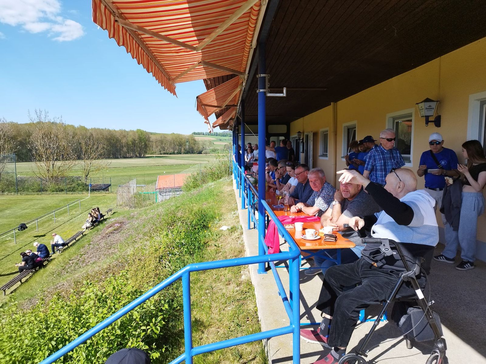 Zuschauer auf der überdachten Terrasse des Clubheims